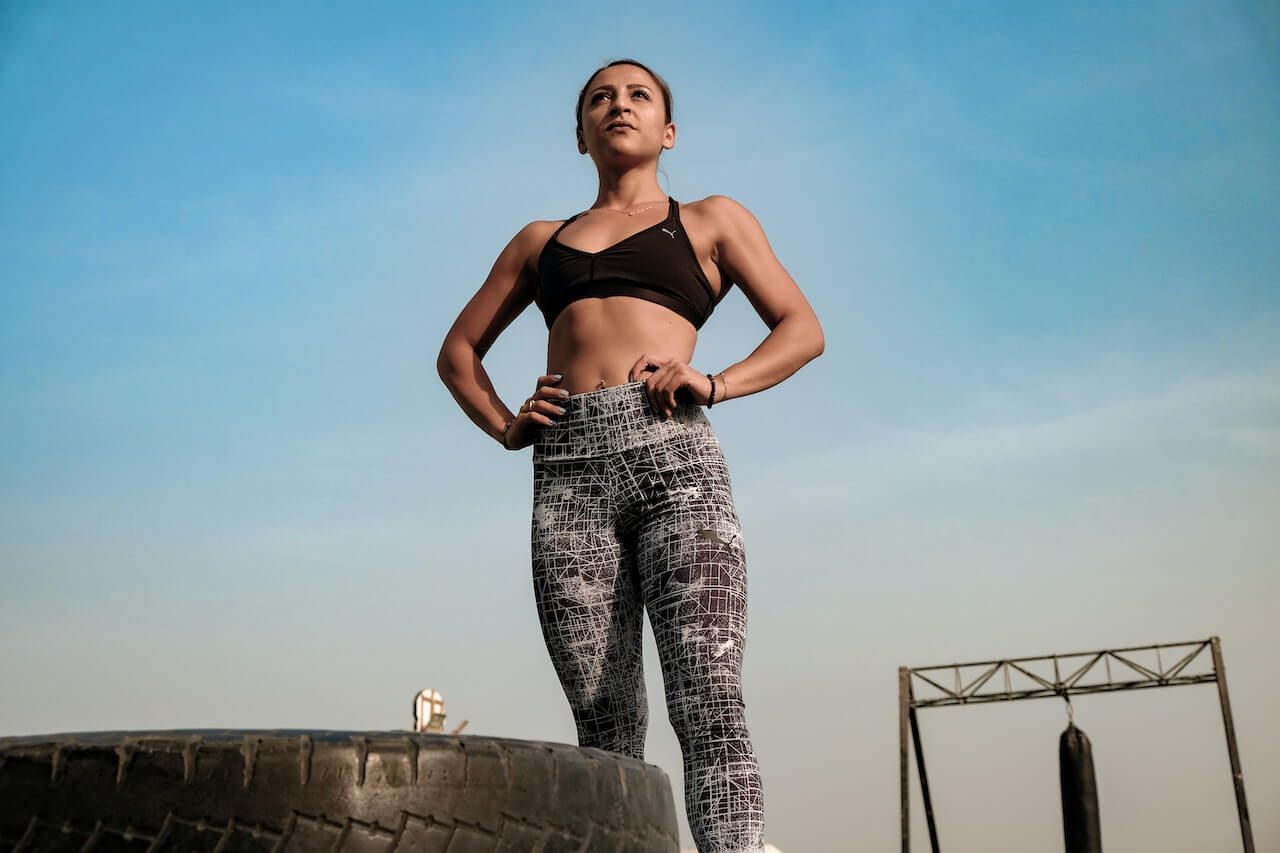 A confident woman in workout attire standing tall with her hands on her hips, ready for a challenging workout.
